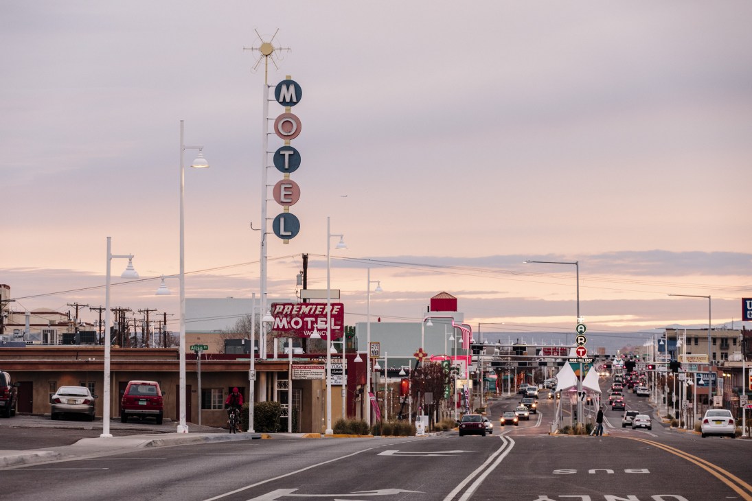 Vintage neon motel signs along historic Route 66 in Albuquerque at sunset with mountains in background