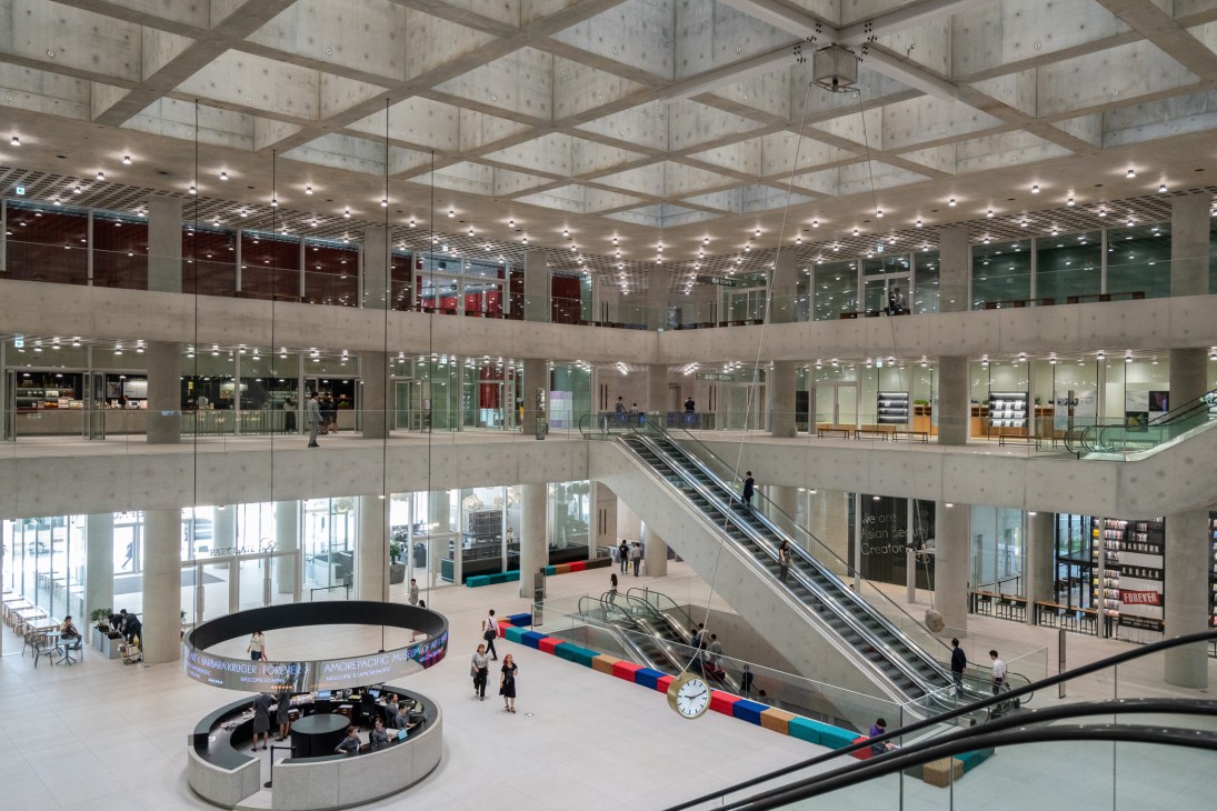 Fifth-floor lobby of Amorepacific headquarters with open-plan design, skylights, escalators, and multiple levels visible.