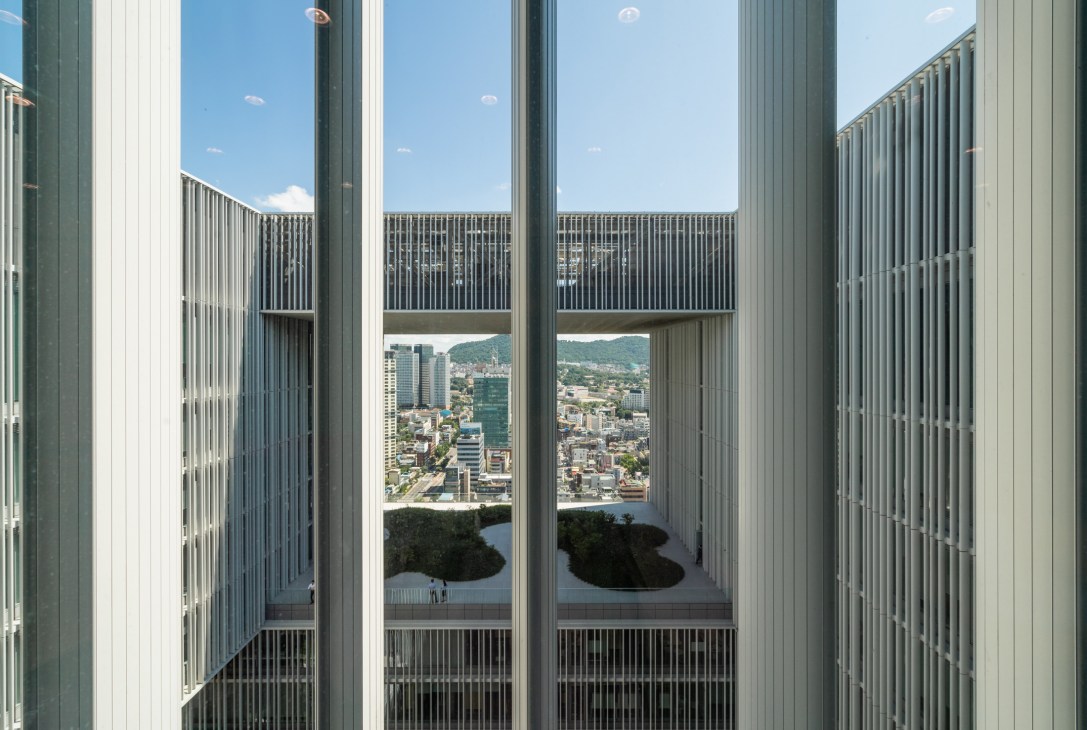 Seoul cityscape view through floor-to-ceiling windows with metal screens at Amorepacific headquarters.