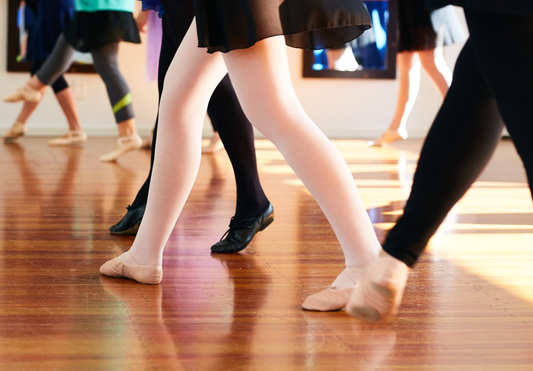 Close-up of ballet dancers' feet and legs in pointe shoes and tights during a Senior Swans class in Auckland.