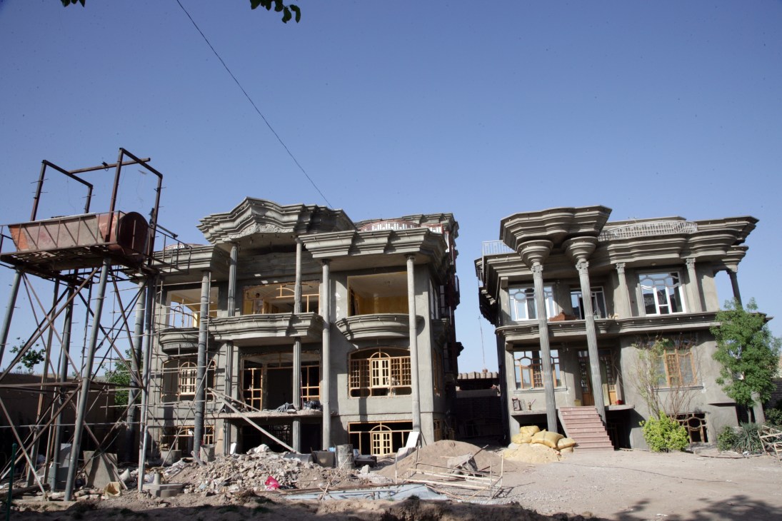 Two unfinished concrete mansions under construction with ornamental columns and decorative architectural details in Herat, Afghanistan.