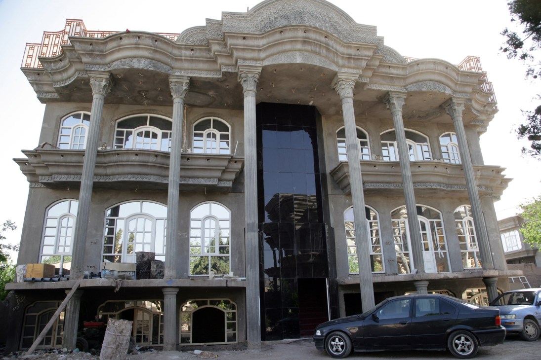 A large neoclassical mansion under construction in Herat with Corinthian columns and parked cars in front.