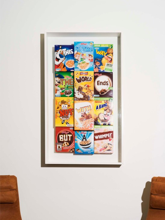 Framed artwork by Finnish artist Jani Leinonen composed of cereal box fronts arranged in a grid spelling out text.
