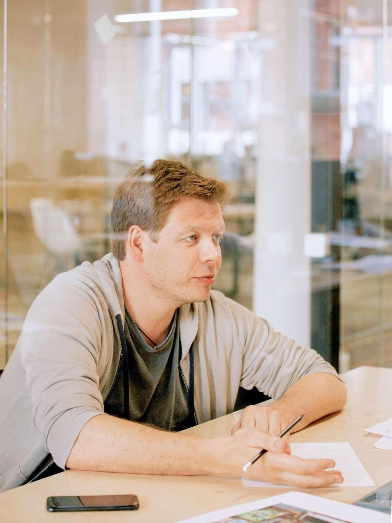 Denis Leontiev, CEO of Strelka KB, sits at a table in a modern office with glass walls behind him.