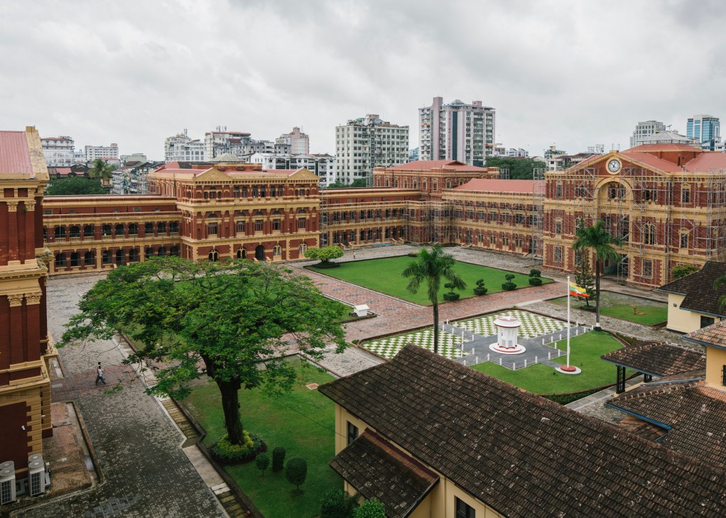 Aerial view of the colonial Secretariat building courtyard with red brick architecture and green lawns in Yangon