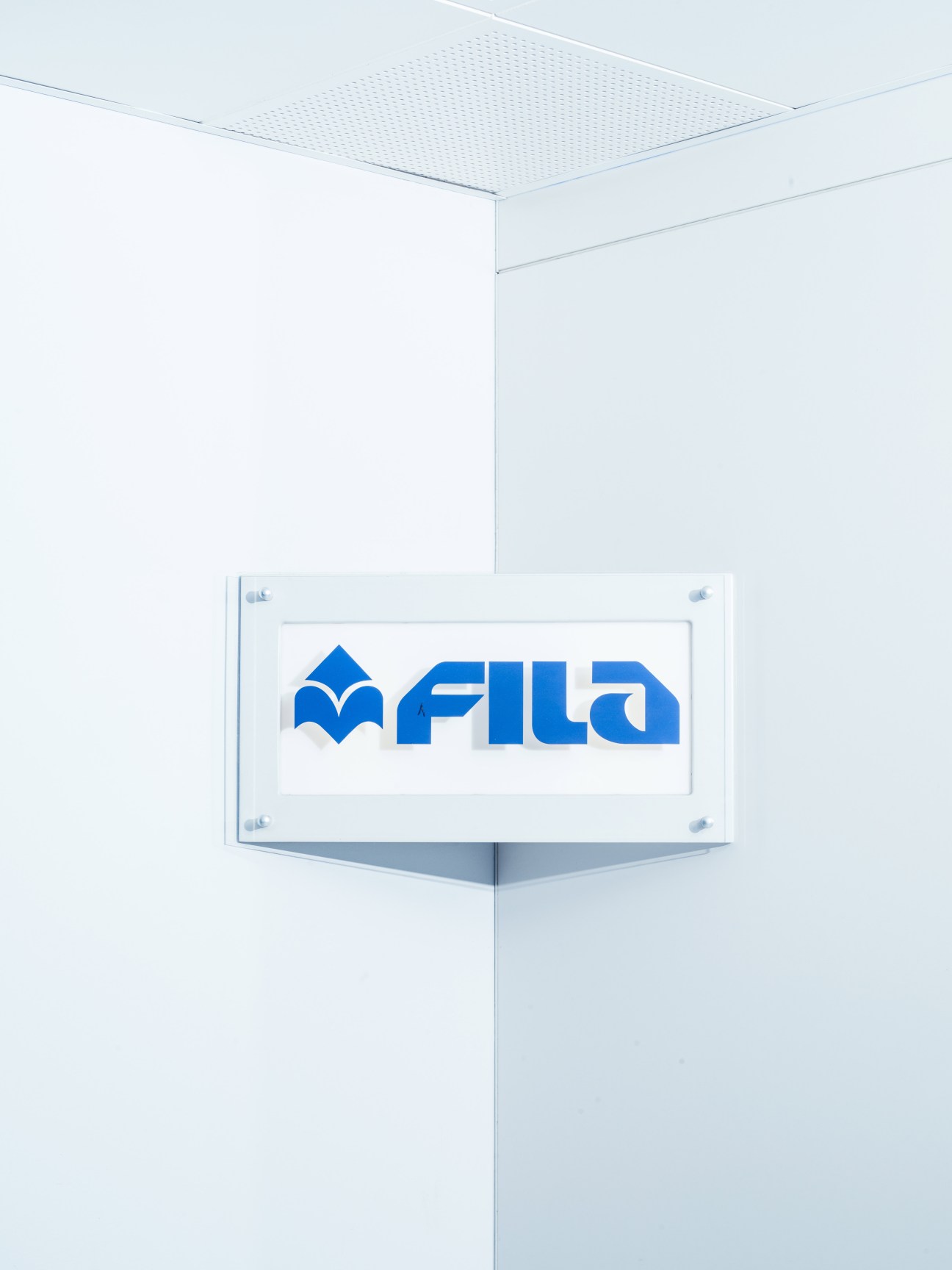 Fila logo sign mounted on white wall at company headquarters in Pero, Milan