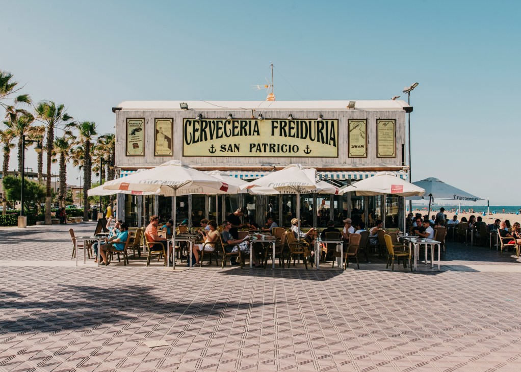 Cervecería Freiduria San Patricio beachside bar with white umbrellas and diners on Valencia's Patacona Beach.