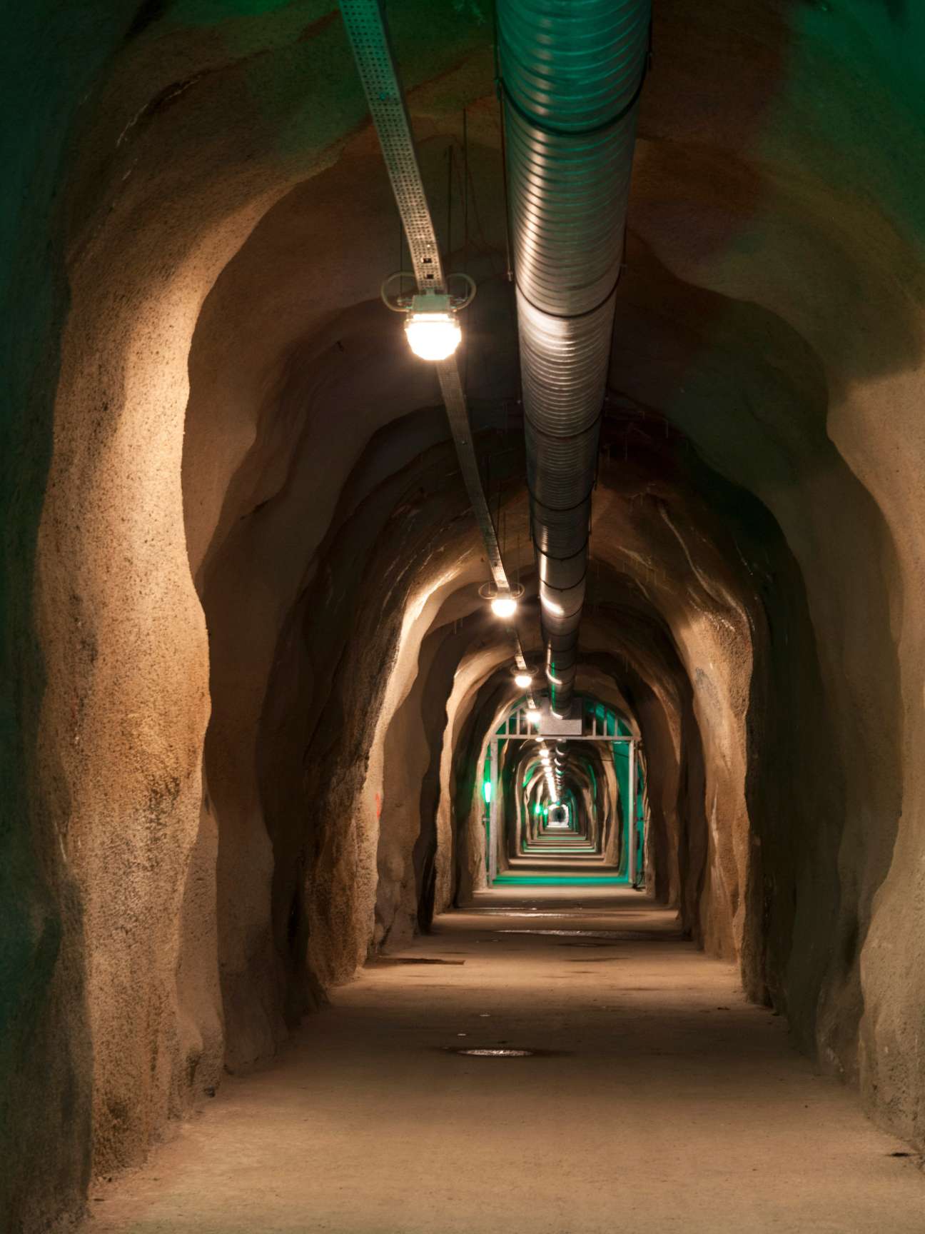 Underground tunnel with illuminated green gates receding into distance at Barbarastollen archive.