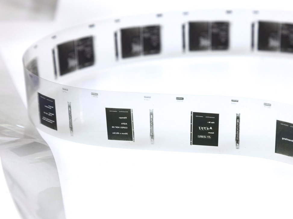Close-up of white cylindrical metal barrels containing microfilm with labeled documentation tags attached.