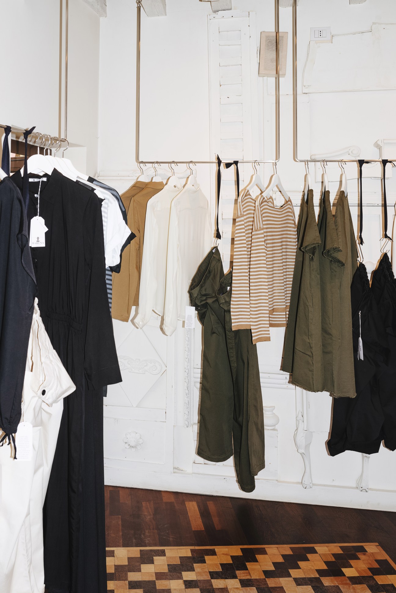 Barena womenswear displayed on wooden hangers against a white wall in the shop
