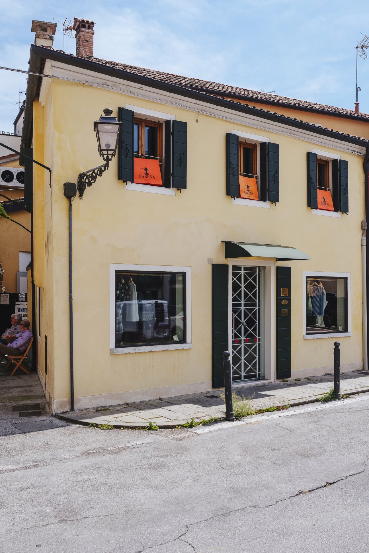 Yellow Venetian-style building with black shutters and Barena shop signage on orange window frames.