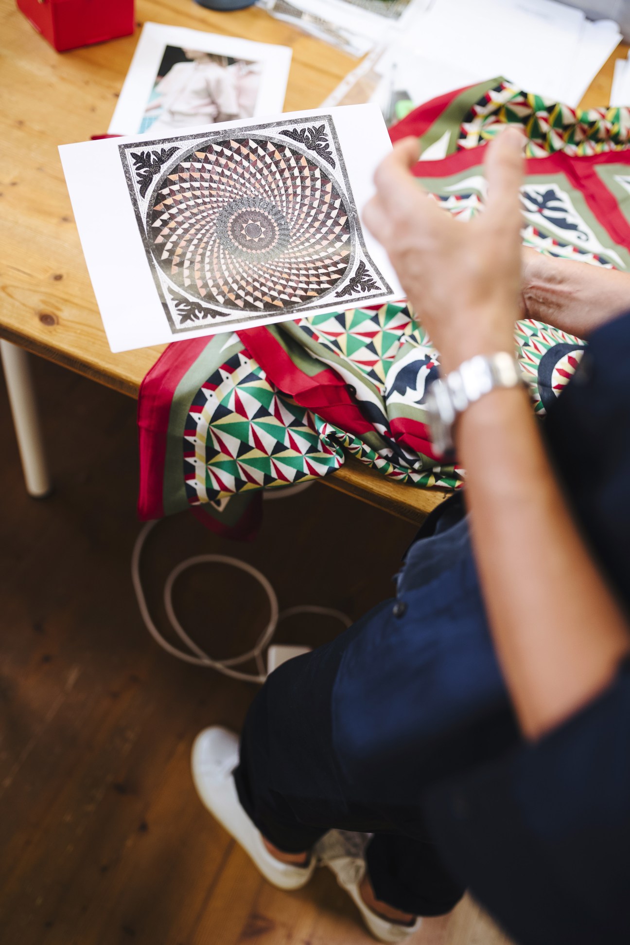 Person holding geometric pattern design inspired by St Mark's Basilica floor with Venetian textile samples.