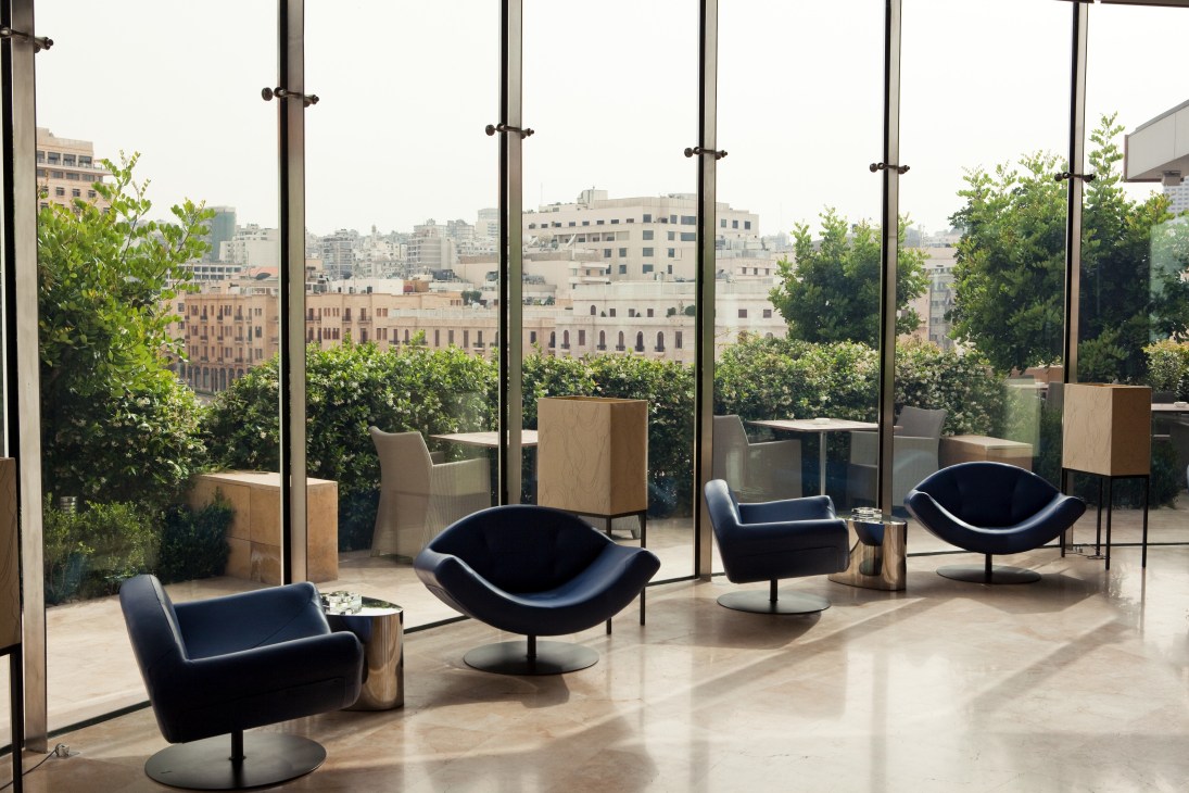 Modern lounge with black curved chairs overlooking Istanbul cityscape through floor-to-ceiling windows.