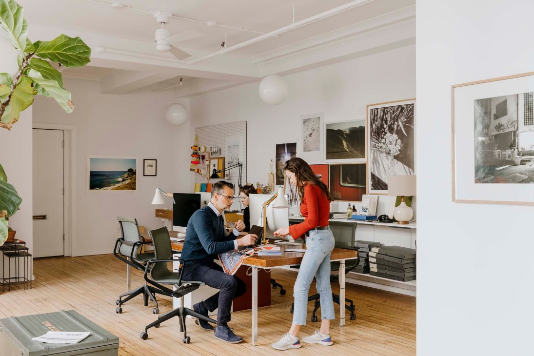 Studio director Rafael Weil meets with a colleague at a desk in a bright white office with art on walls.