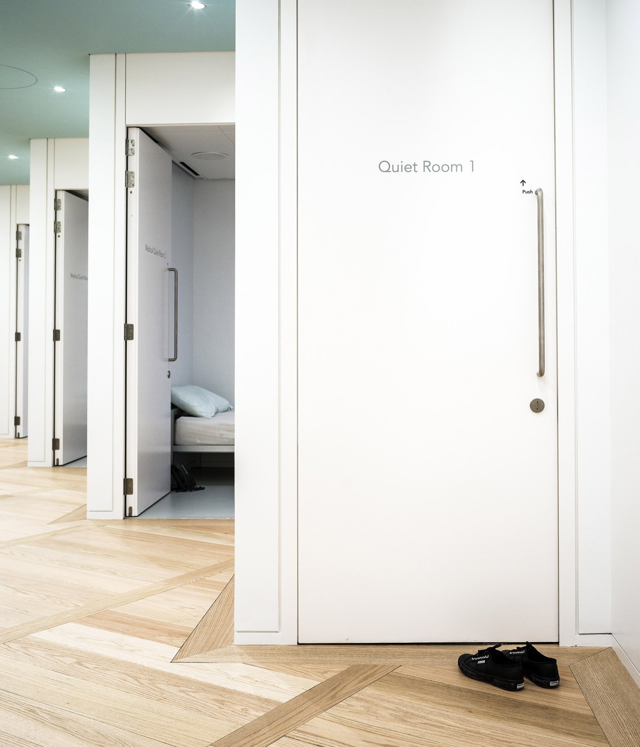 Wellness centre quiet room with white door labeled 'Quiet Room 1' and minimalist interior design