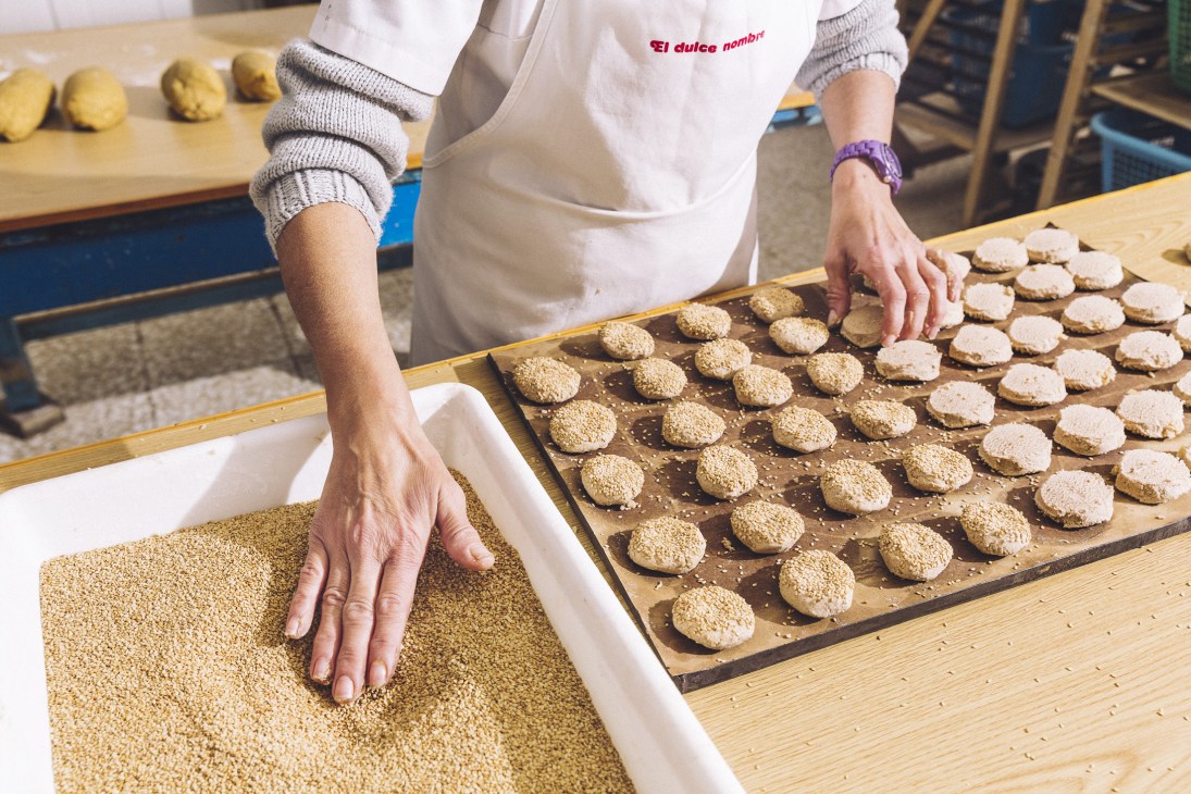 Worker coating mantecados in sesame seeds at El Dulce Nombre factory in Estepa.