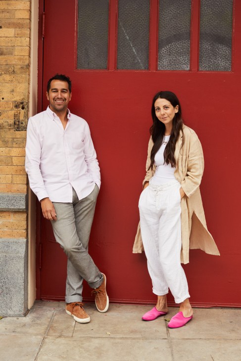Dustin Lancaster and Sally Breer stand against a bright red door in the Firehouse Hotel's Arts District location.