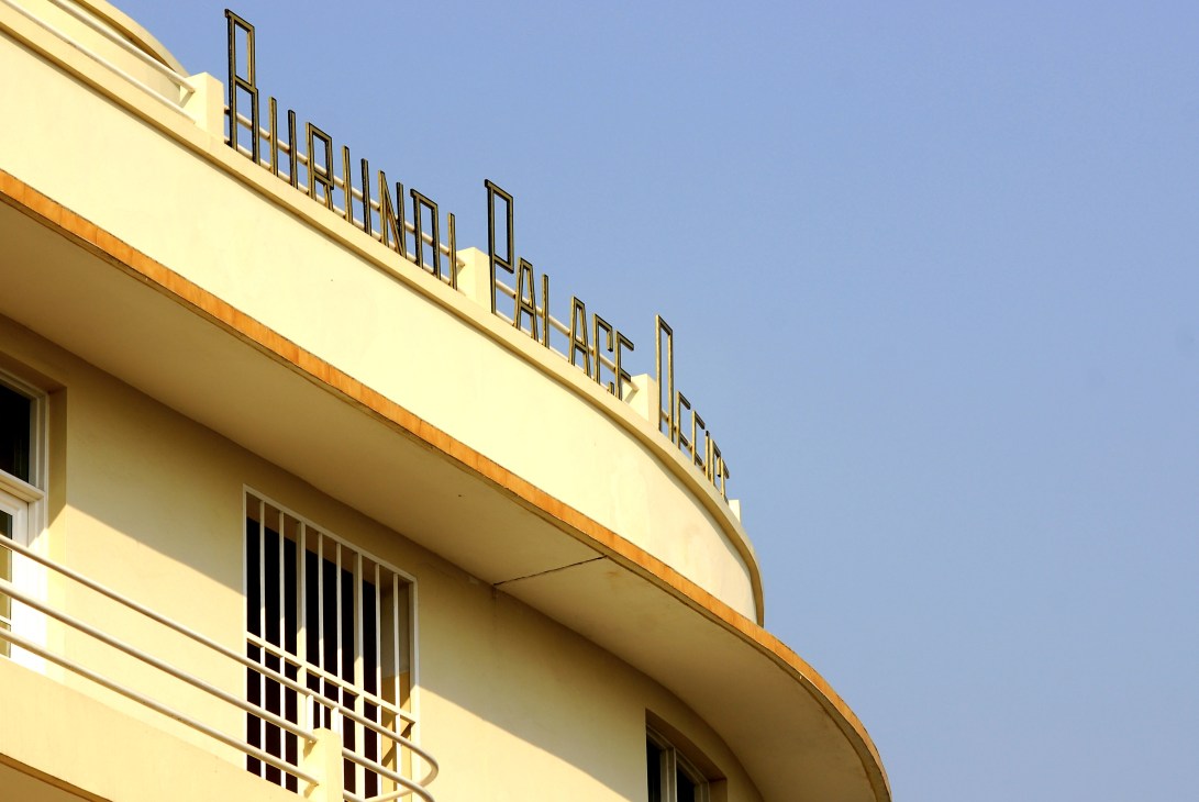 Yellow art-deco facade of Burundi Palace Hotel with curved architectural details.
