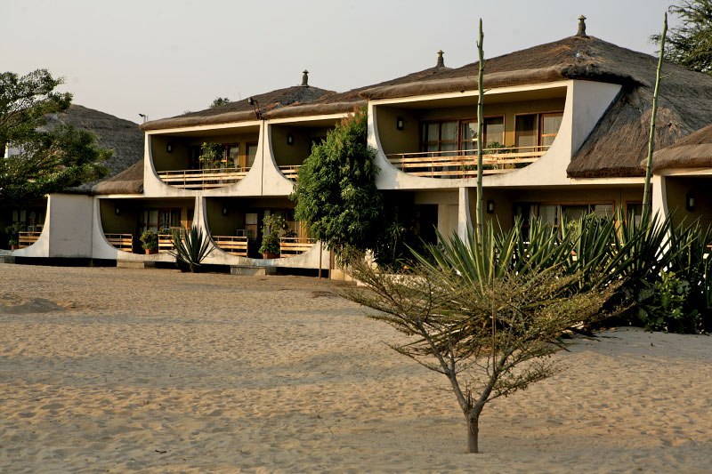 Hotel Club du Lac Tanganyika, a white building with thatched roofs on a sandy beach.