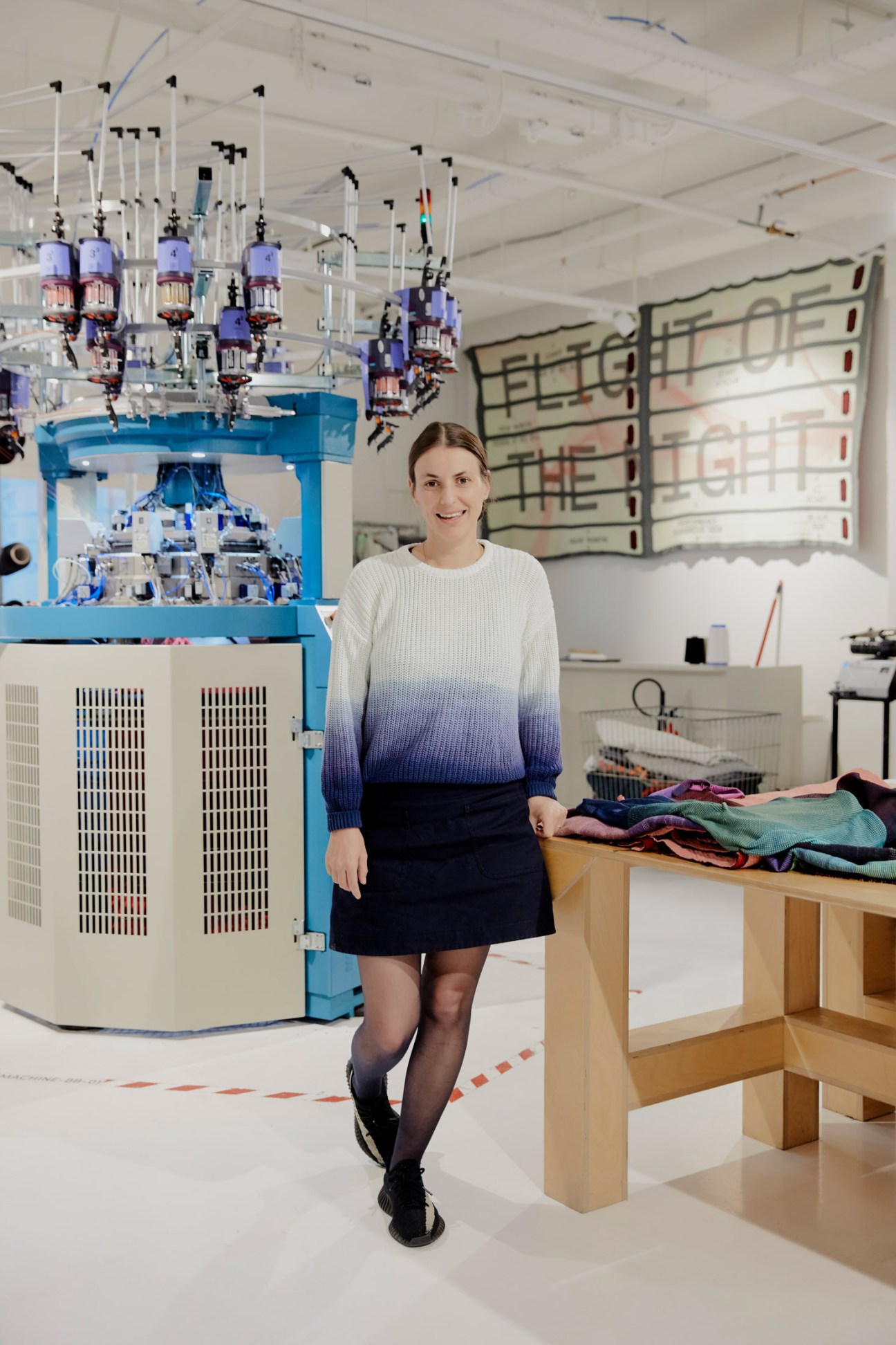 Senior knit engineer Annemarie Reedijk standing in Byborre's textile lab with knitting machinery.