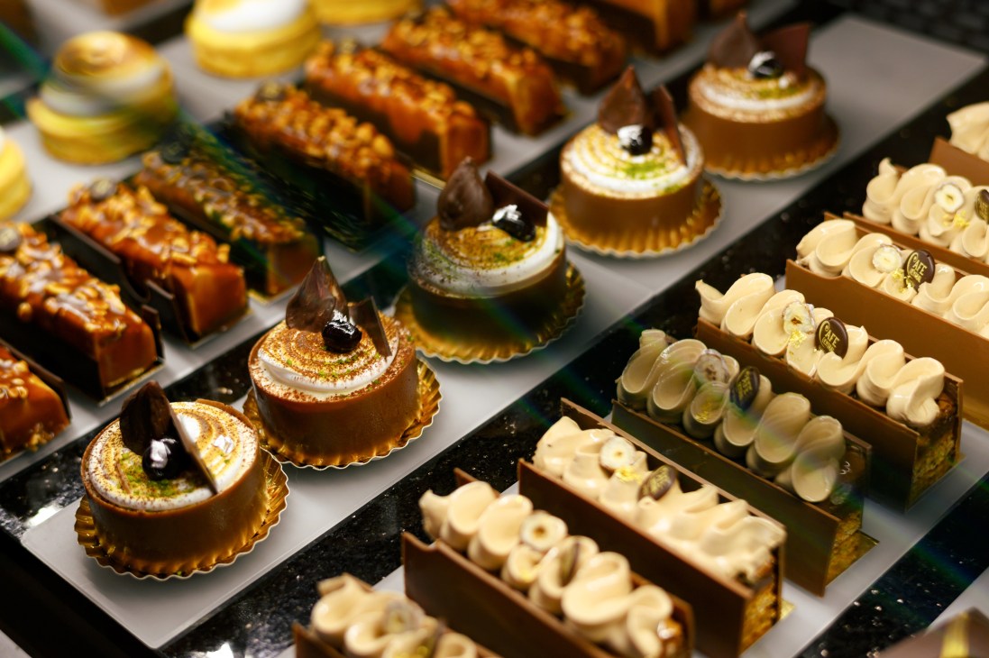 Display case of elegant petit fours and pastries with decorative toppings and chocolate garnishes