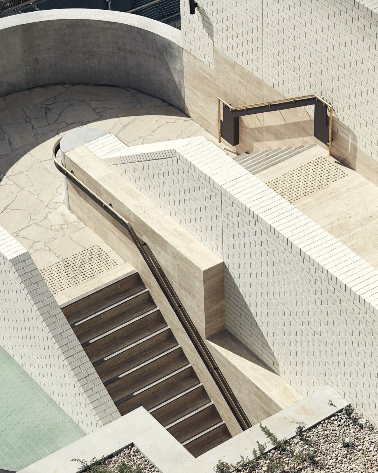 Aerial view of The Calile hotel's staircase descending to street level with travertine floors and architectural details.