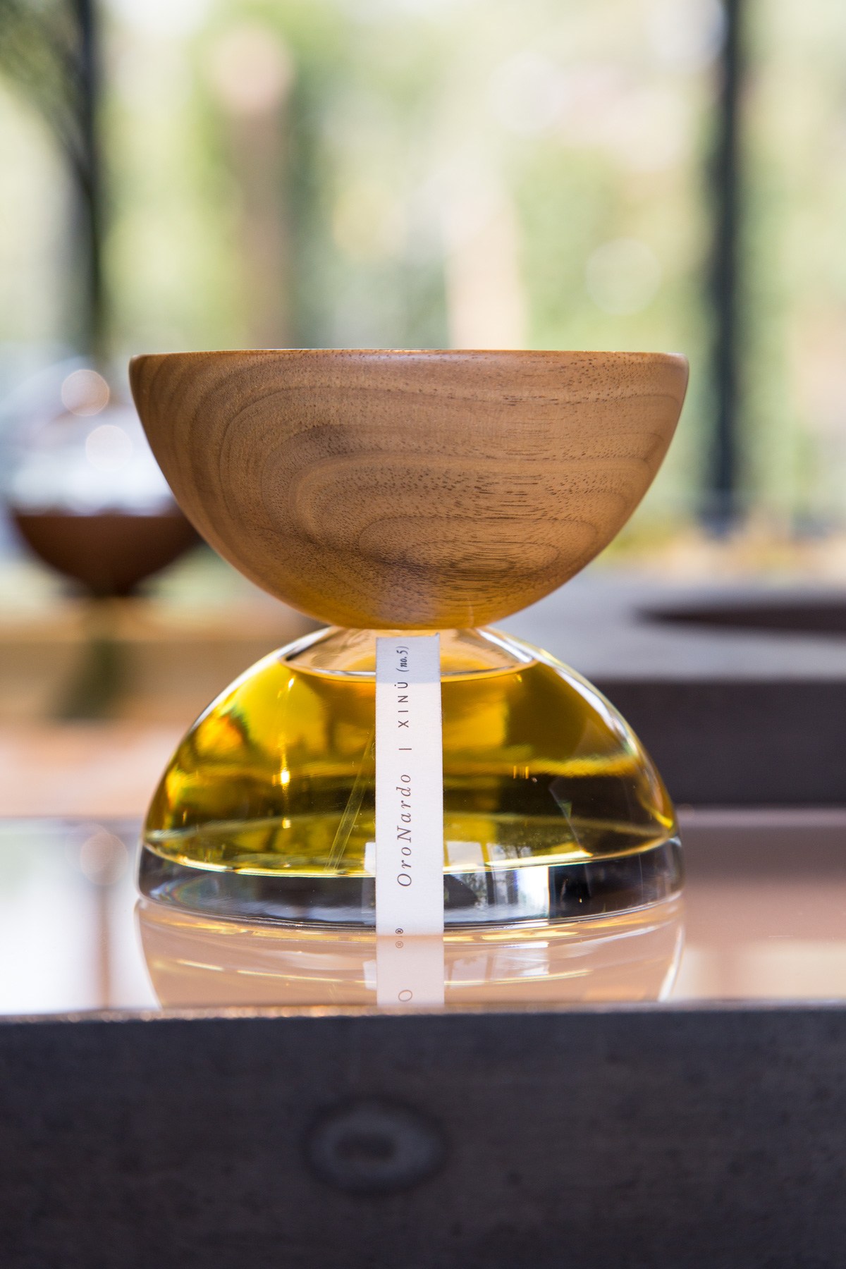 Perfume bottle with wooden cap and Oporarrdo Xinú label displayed outdoors.