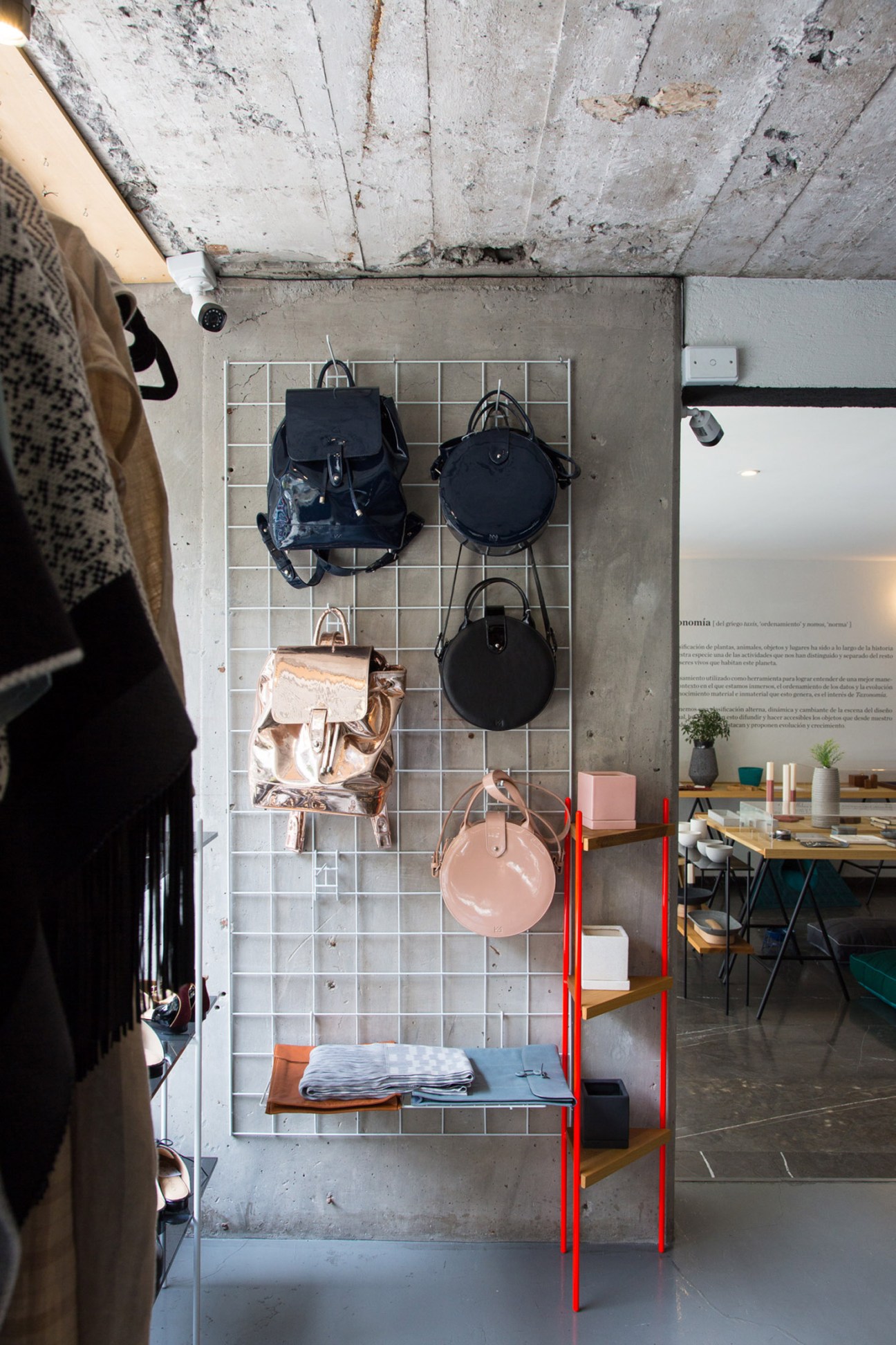 Juana la Loca bags displayed on a white grid wall panel in a retail setting.