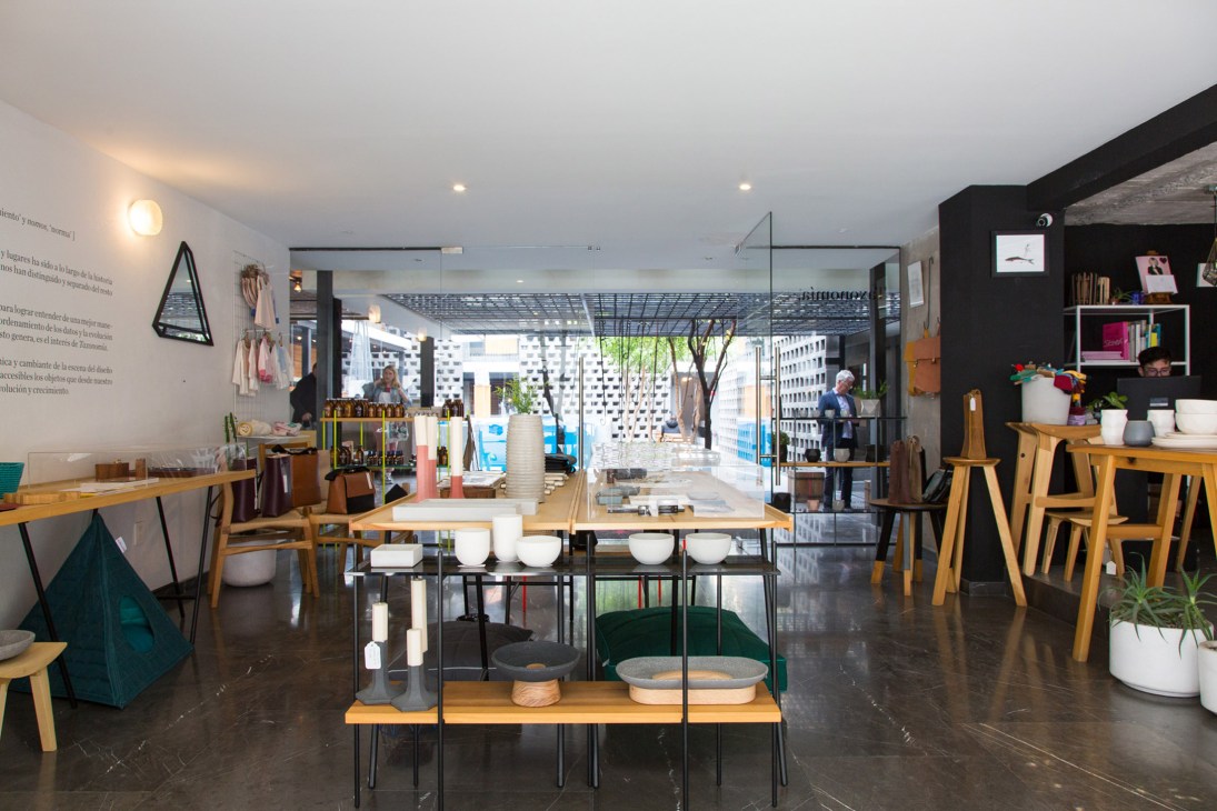 Interior view of Taxonomía design shop displaying contemporary Mexican furniture, ceramics, and homeware across wooden tables and shelving.