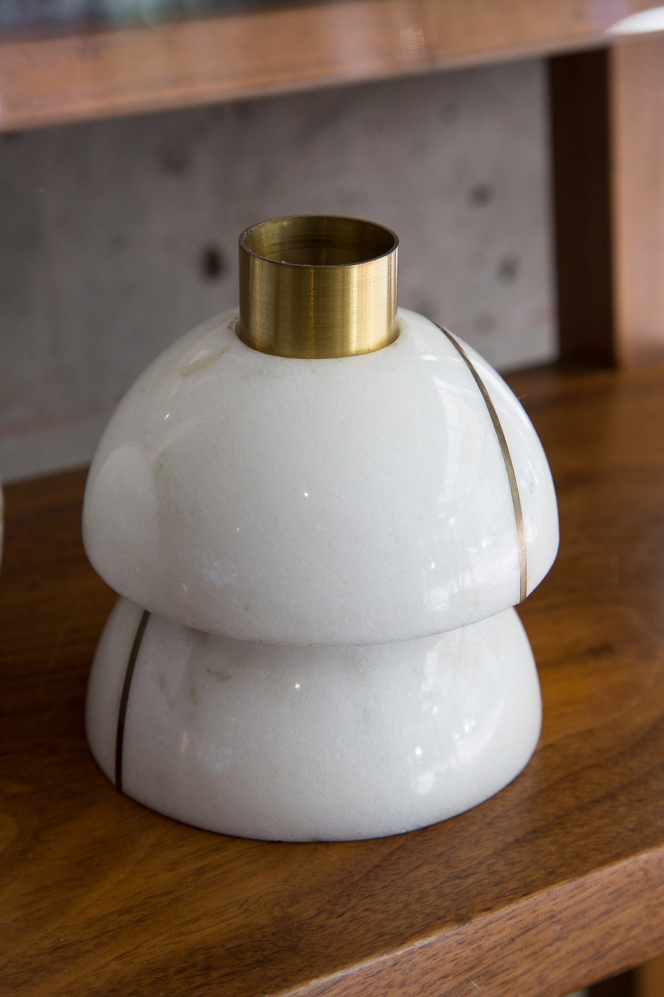 White ceramic candleholder with brass rim by Peca displayed on wooden surface.