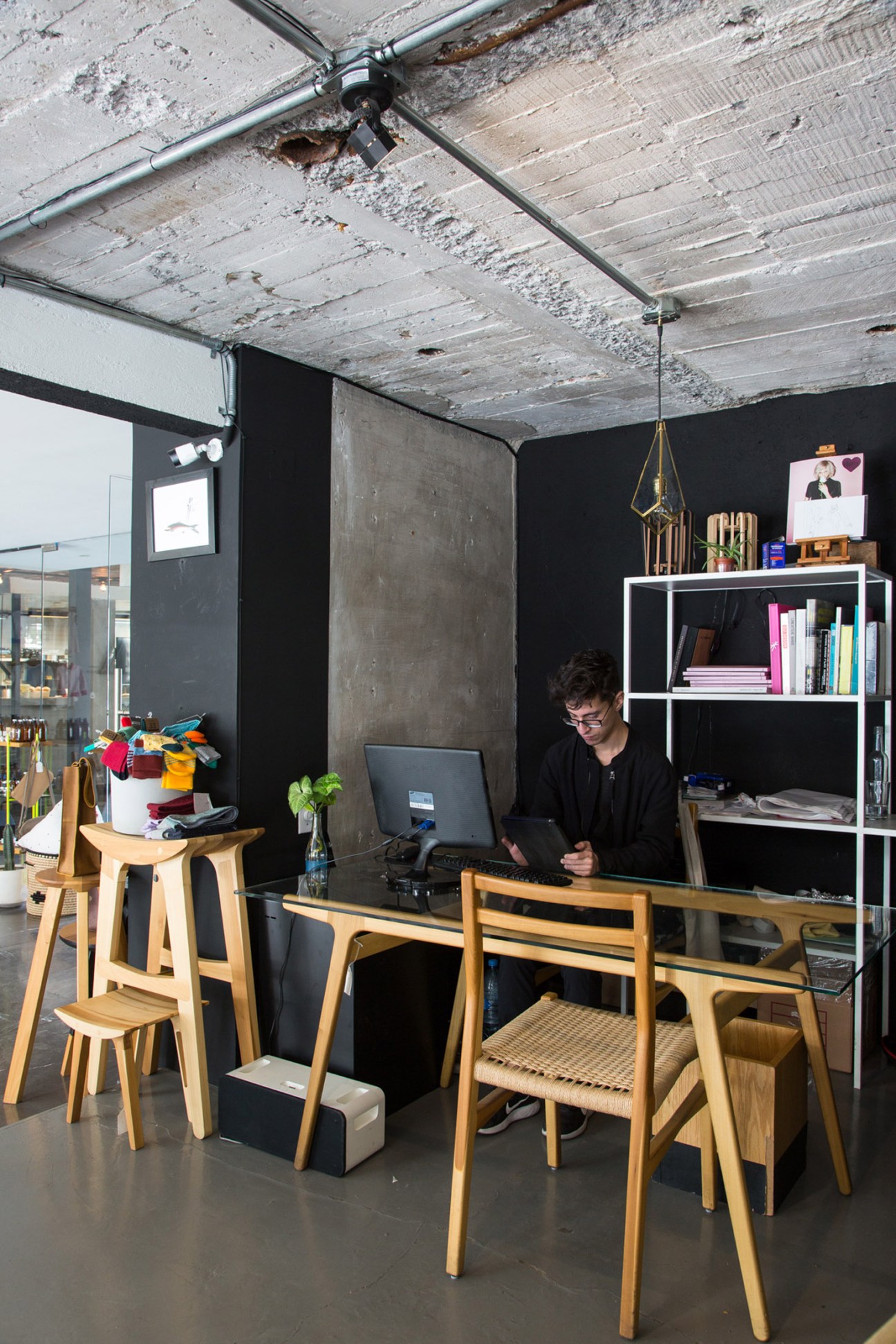 Interior of Taxonomía shop showing a woman working at a wooden desk with modern Mexican design products and furniture displayed.