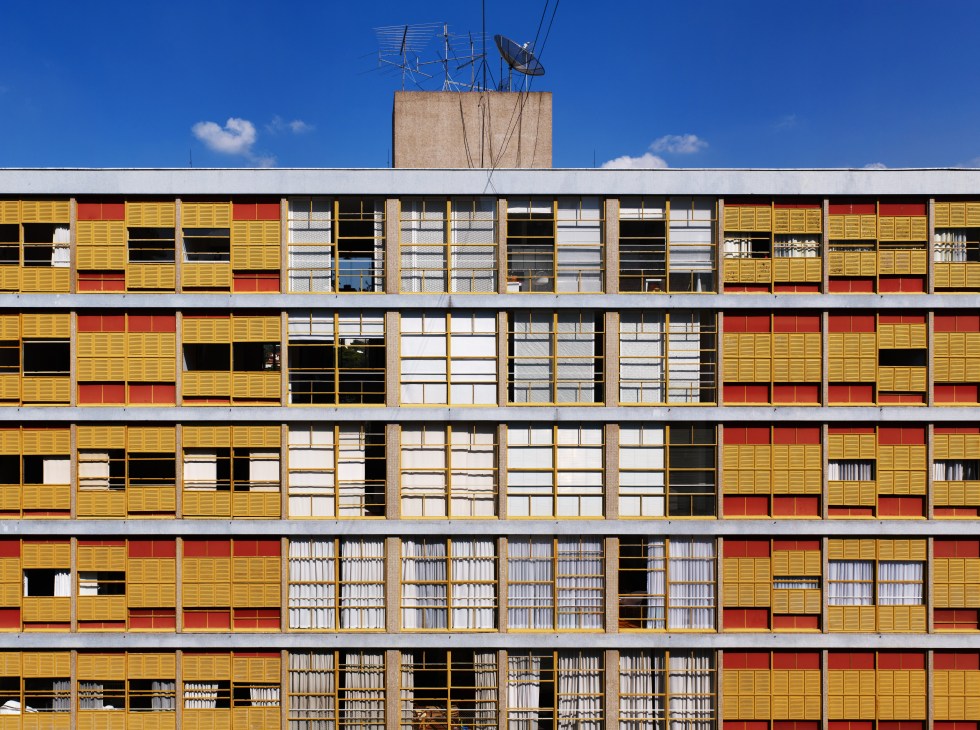 Colorful modernist apartment building façade with yellow and red shutters and antenna on roof