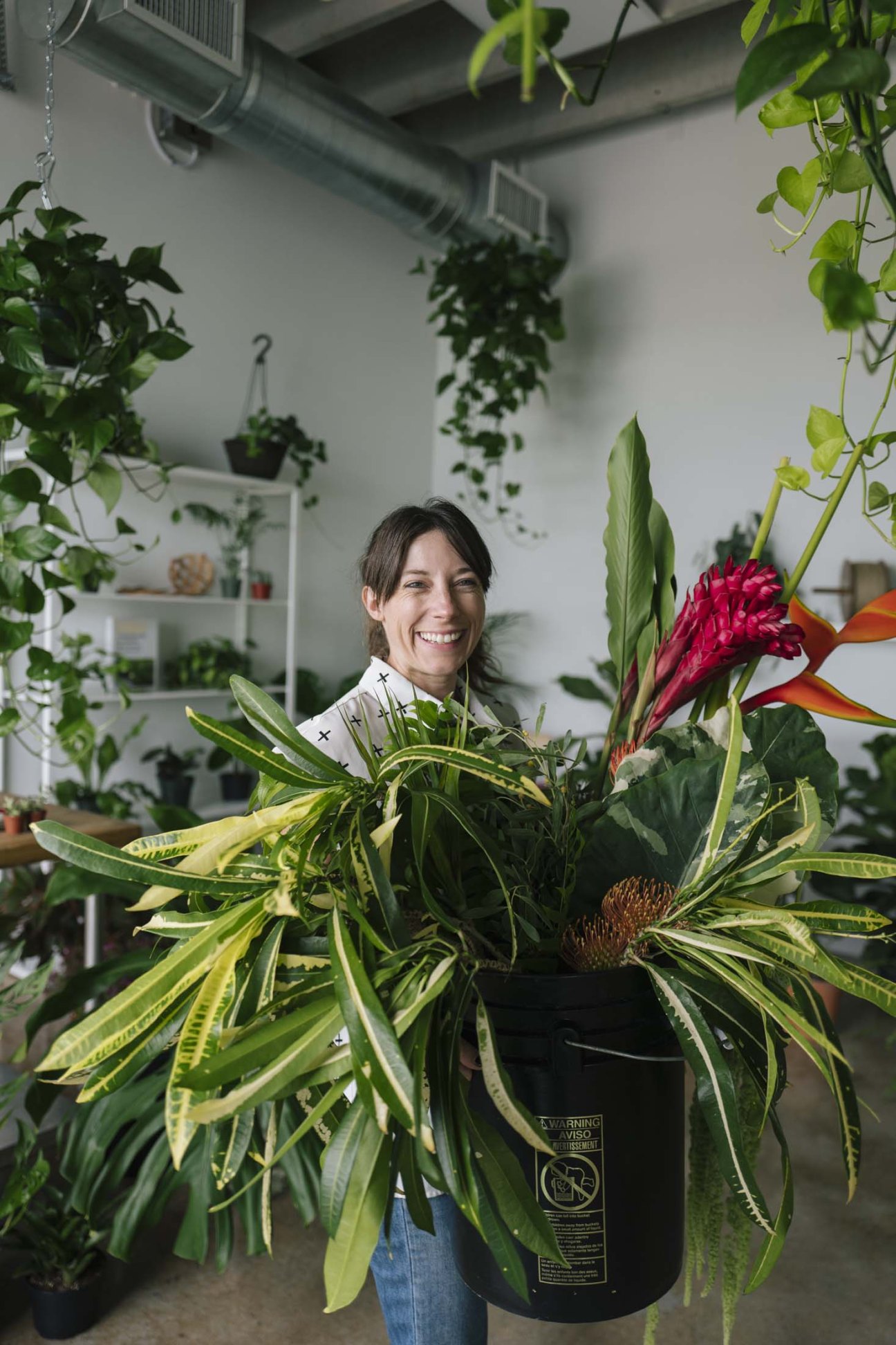 Sara Rose Darling arranging flowers in her studio space with plants and floral displays