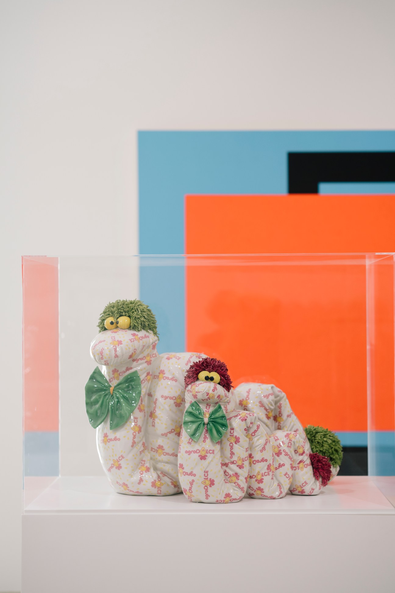 Jeff Koons' 'Serpents' sculpture featuring white fabric figures with colorful yarn hair and green bows