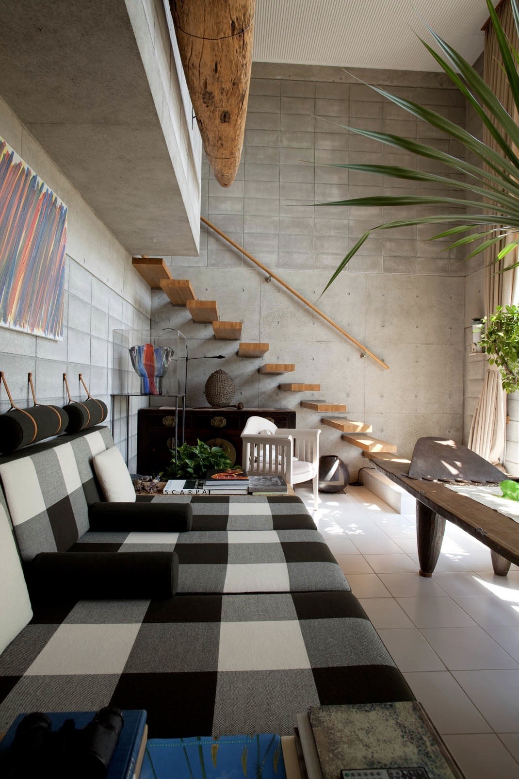 Modern interior with Børge Mogensen sofa and Eliel Saarinen chair beside wooden stairs and potted plants.