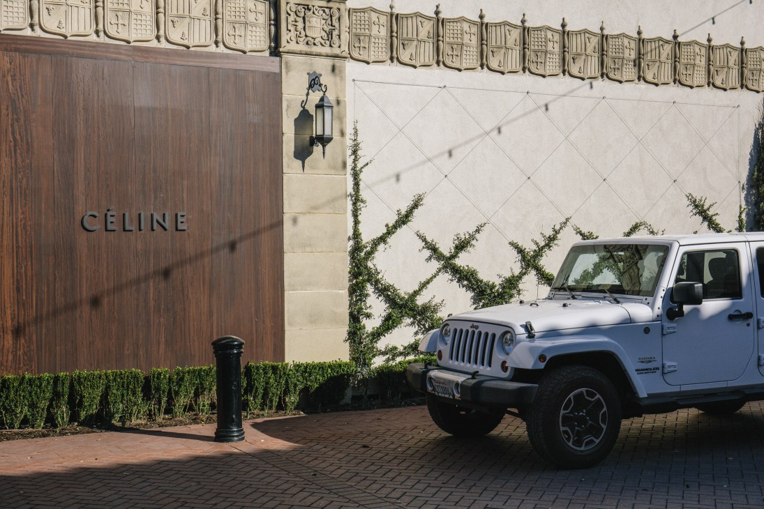 White Jeep parked outside Celine storefront with ivy-covered wall and ornate architecture.