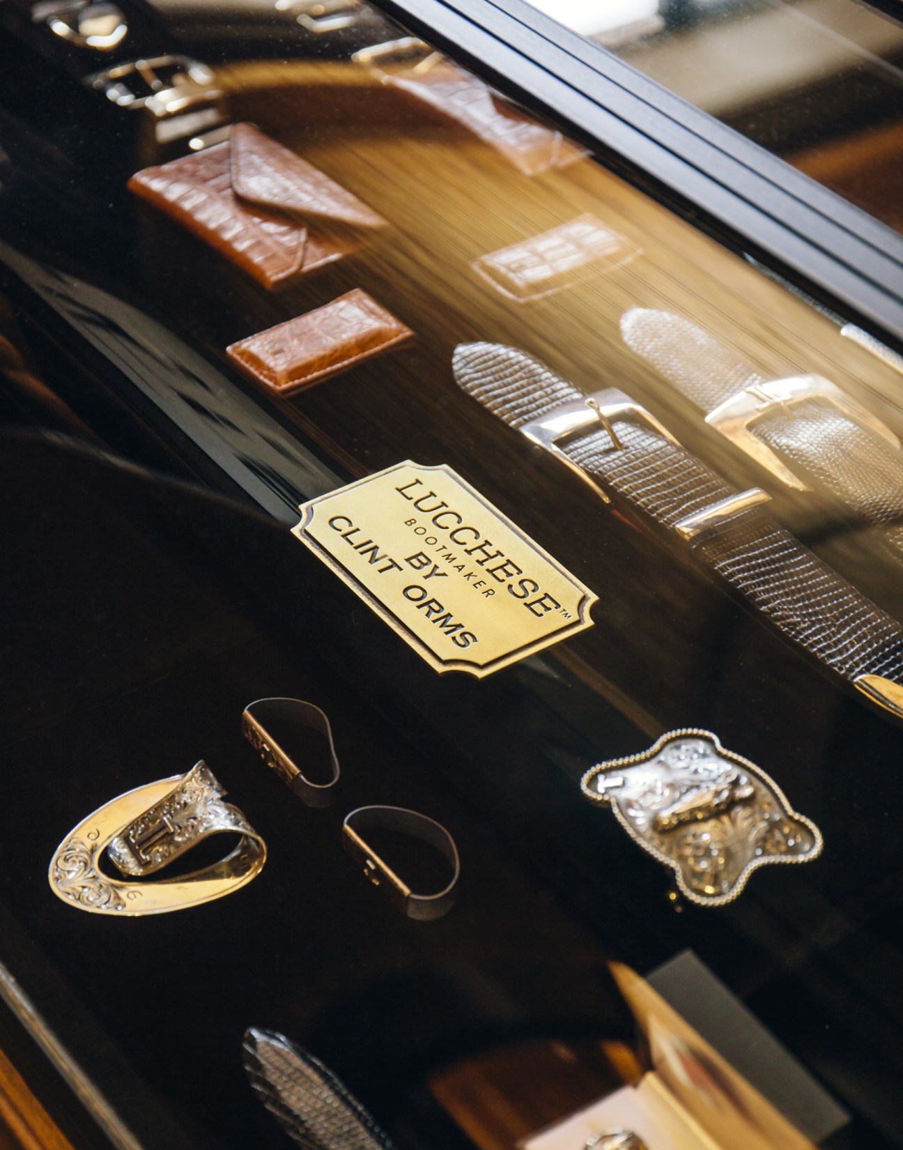 Lucchese leather belt buckles and accessories displayed in a case at Neiman Marcus.