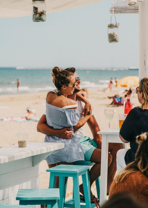 Couple enjoying drinks at a beachside chiringuito overlooking Valencia's Patacona Beach.