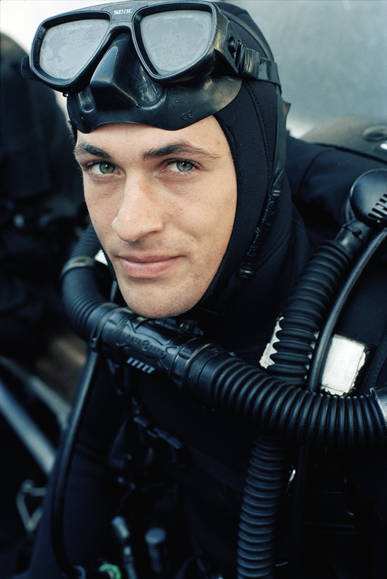 A diver in wetsuit and diving equipment surfacing from the water.