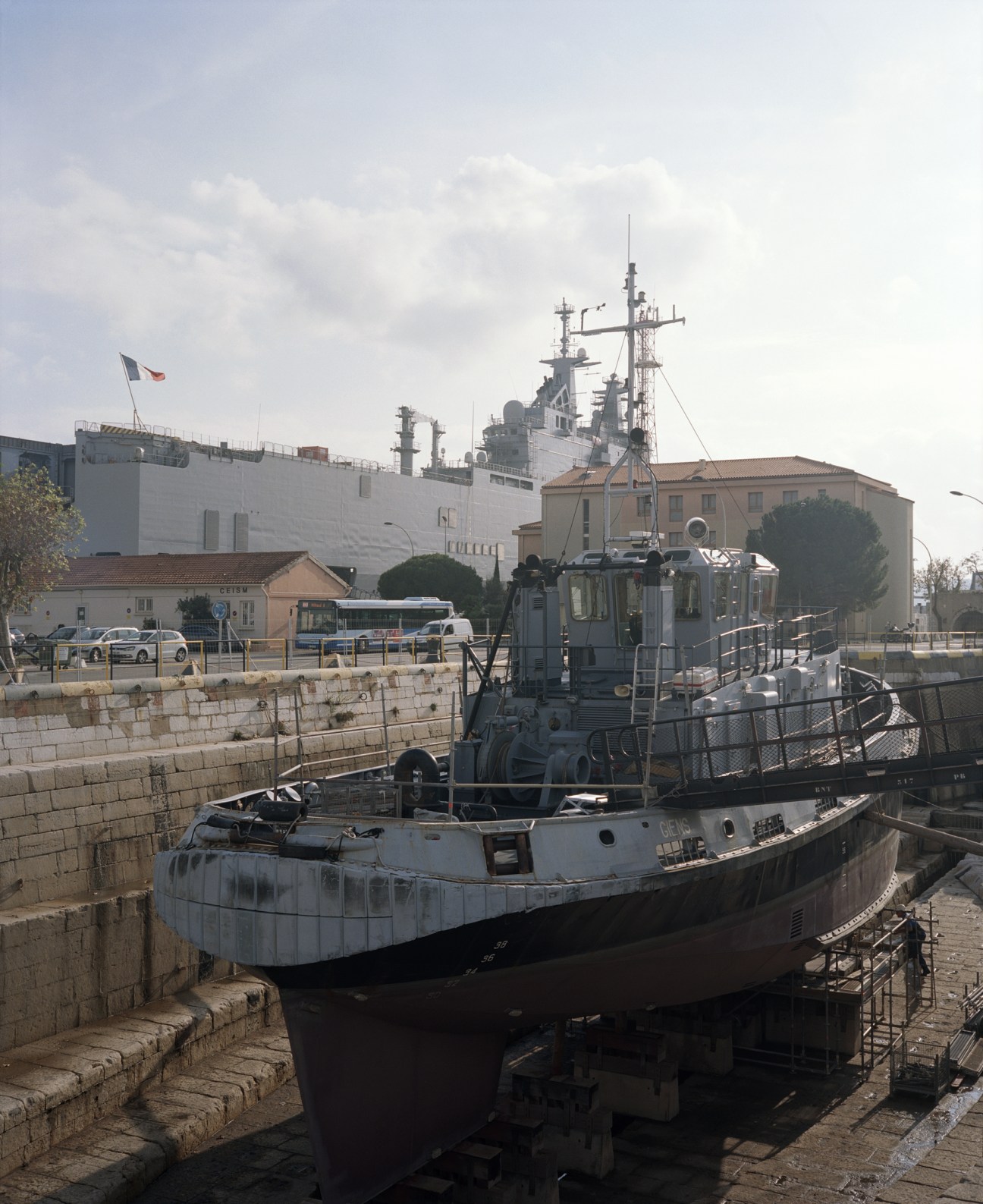 French naval vessels moored at Toulon harbor with military ships and base buildings visible.