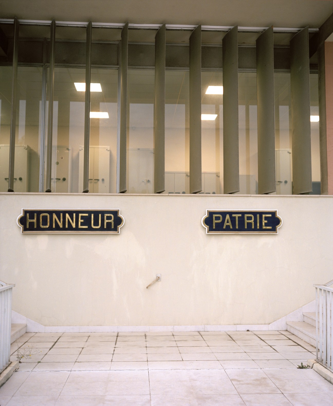 Glass-fronted offices labeled 'Honneur' and 'Patrie' with metal-framed partitions and interior lighting