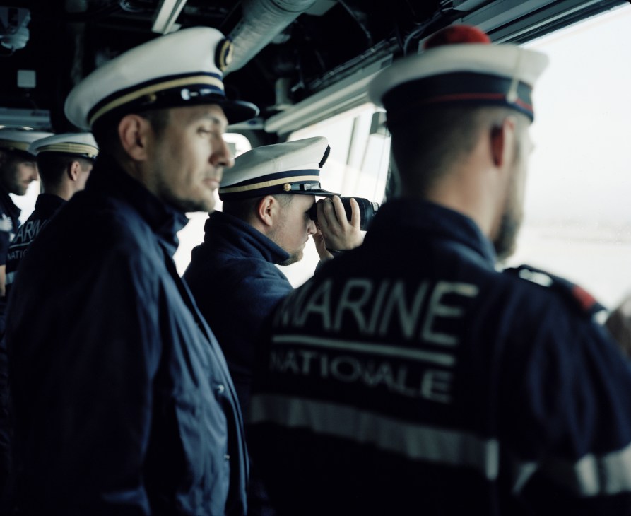 French Navy sailors in uniform on the bridge of the Chevalier Paul destroyer, one operating binoculars.