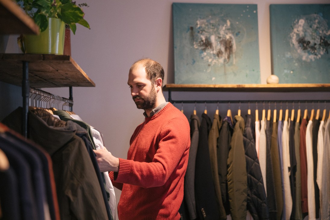 Man in red sweater browsing clothing at Del Diego menswear shop in Madrid.