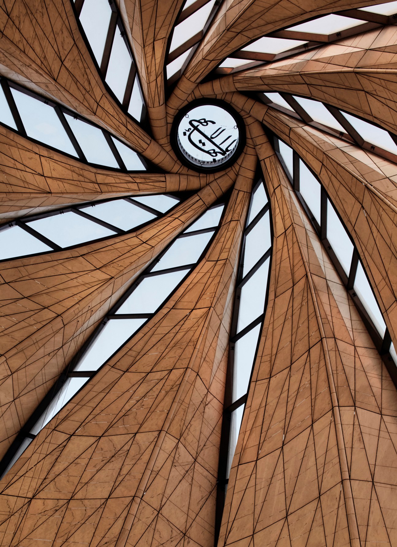 Interior view of the Baha'i House of Worship dome with wooden beams spiraling upward and a circular skylight at the center.