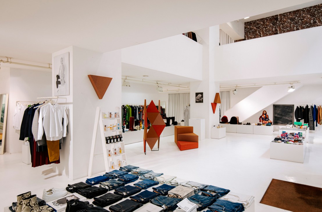 Interior of Park fashion emporium in Vienna showing white walls, clothing racks, geometric copper sculptures, and an orange chair.