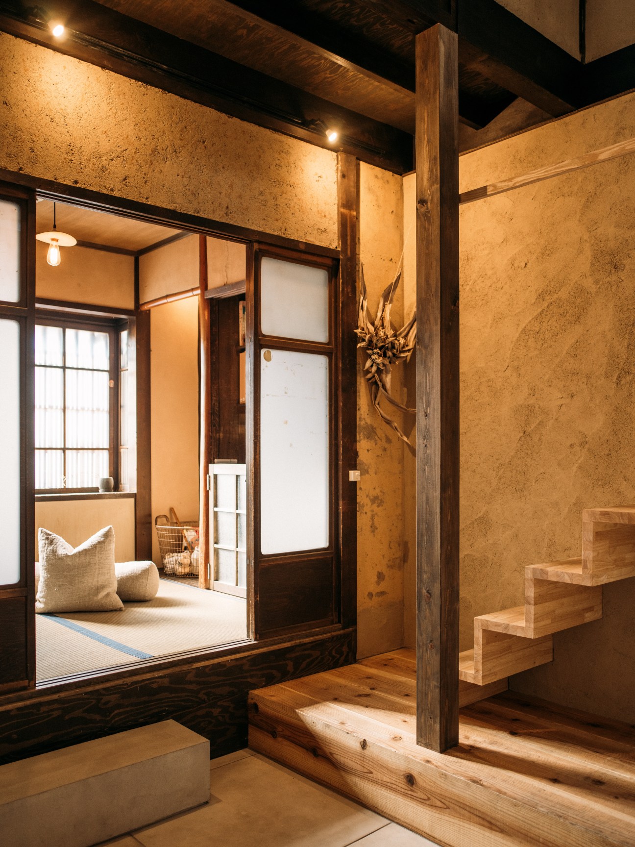 Interior of A Day in Khaki guesthouse showing double-height ceiling space with wooden beams and tatami mat bedroom.