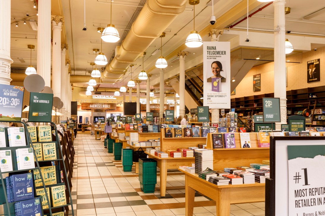 Interior of Barnes & Noble bookstore showing spacious layout with book displays, hanging pendant lights, and classical columns