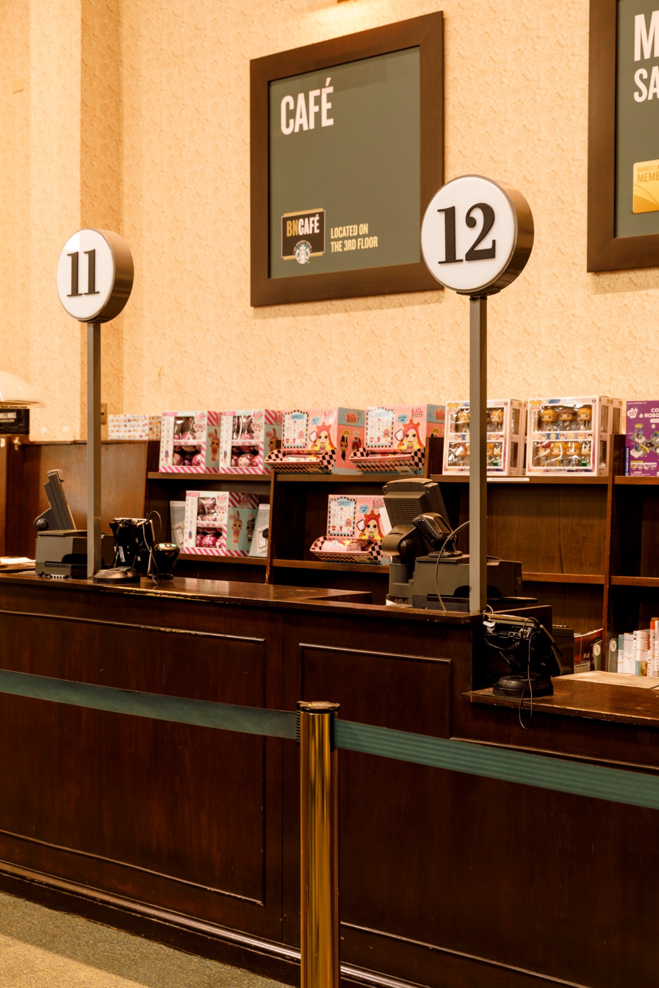 Checkout counter numbered 11 and 12 with card displays and point-of-sale terminals but no books visible