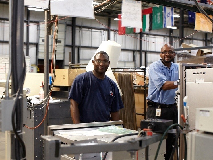 Two Viking factory workers assemble kitchen range components on a manufacturing line.