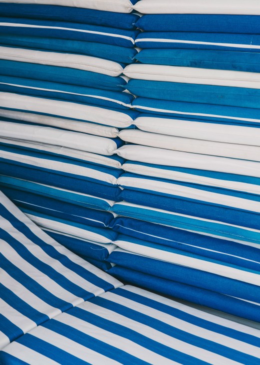 Blue and white striped beach loungers stacked in neat rows.
